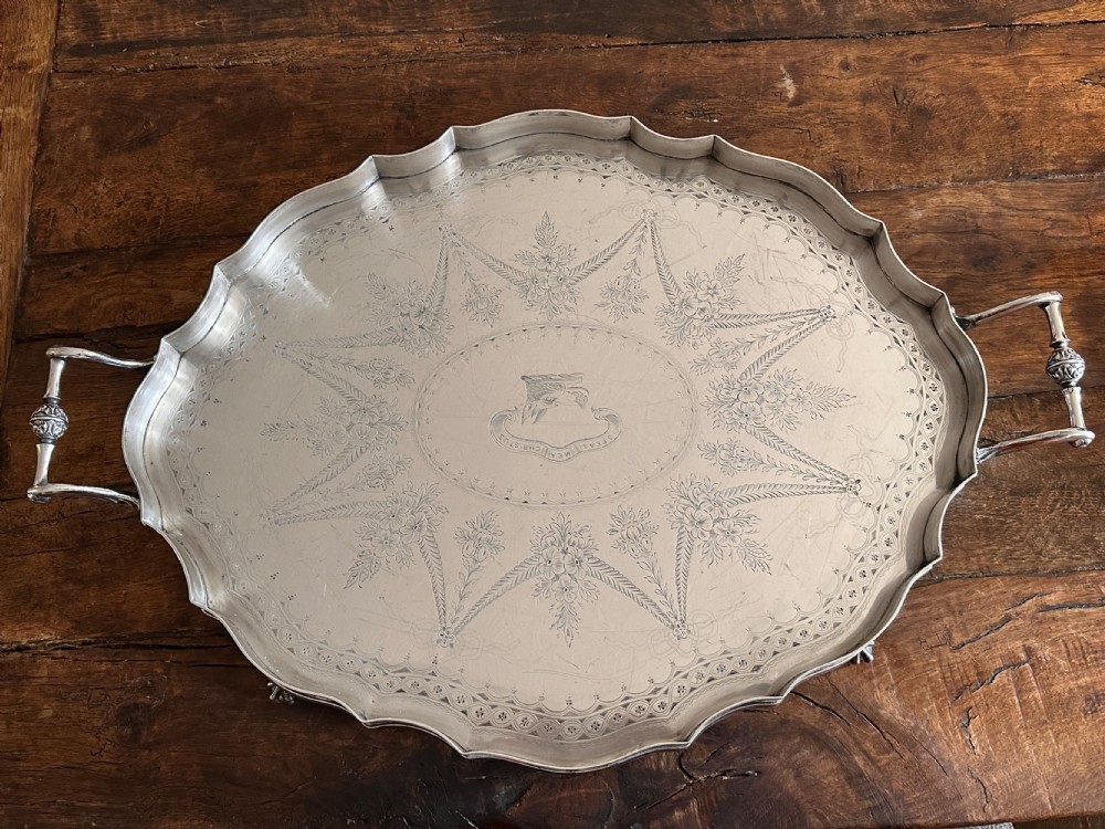 A large oval silver-plated tray featuring a scalloped gallery border, twin side handles, etched foliate surface decoration, and cast feet. View III