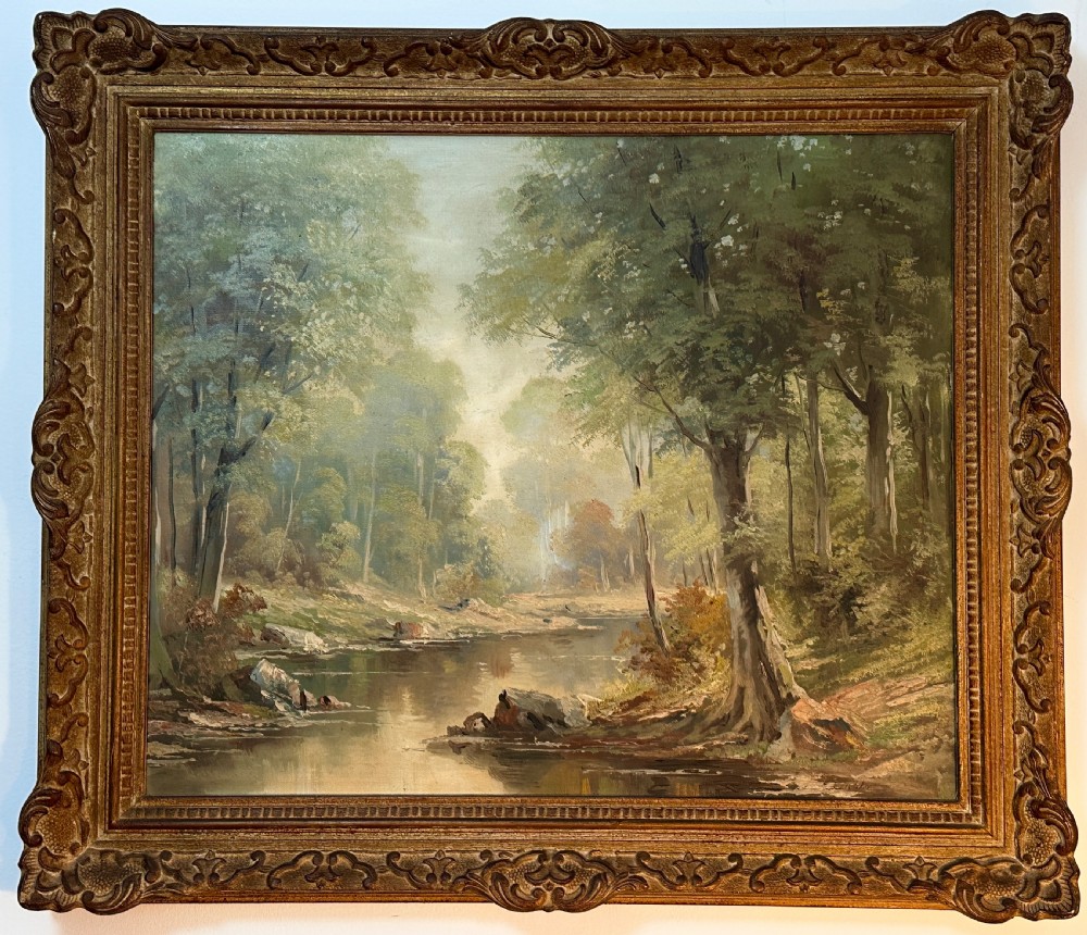 An antique landscape oil painting depicting a calm river flowing through a dense forest, housed in an ornate gilded frame.