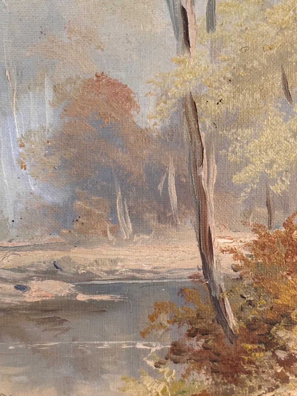 An antique landscape oil painting depicting a calm river flowing through a dense forest, housed in an ornate gilded frame. View V