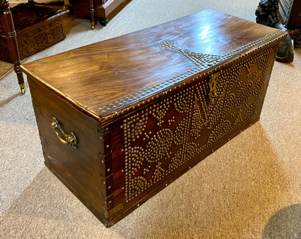 A dark hardwood rectangular chest decorated with intricate geometric patterns made from brass studs and fitted with a decorative central brass lock. View IV