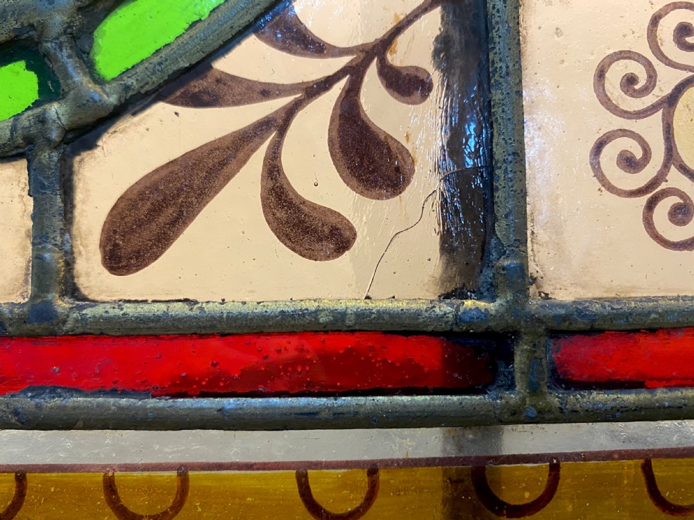A rectangular framed leaded stained glass panel featuring a central painted roundel portrait of William Shakespeare surrounded by colourful geometric patterns. View V
