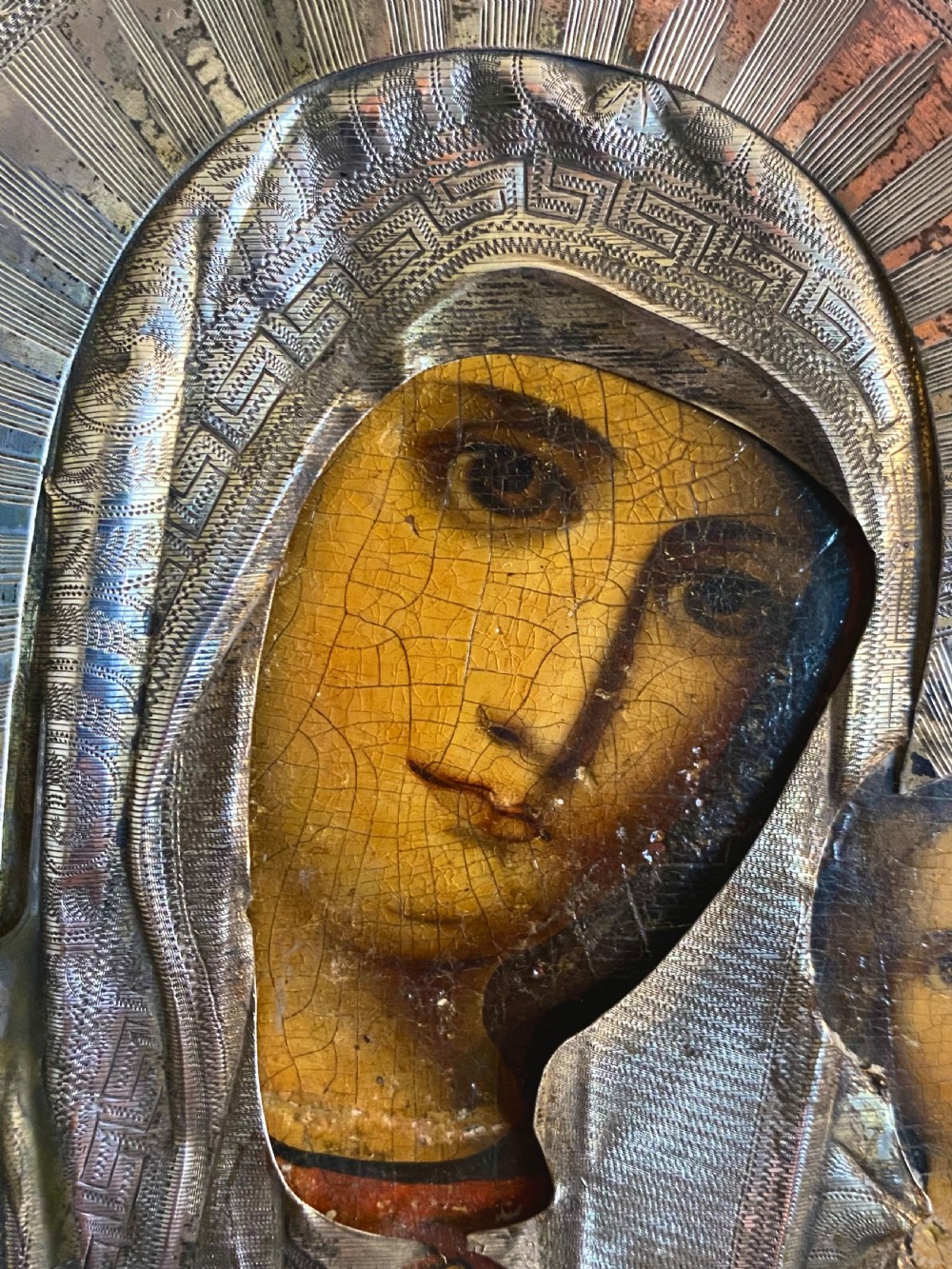 A Russian Orthodox wooden icon encased in an intricately chased silver oklad portraying the Mother of God and Infant Christ. View II