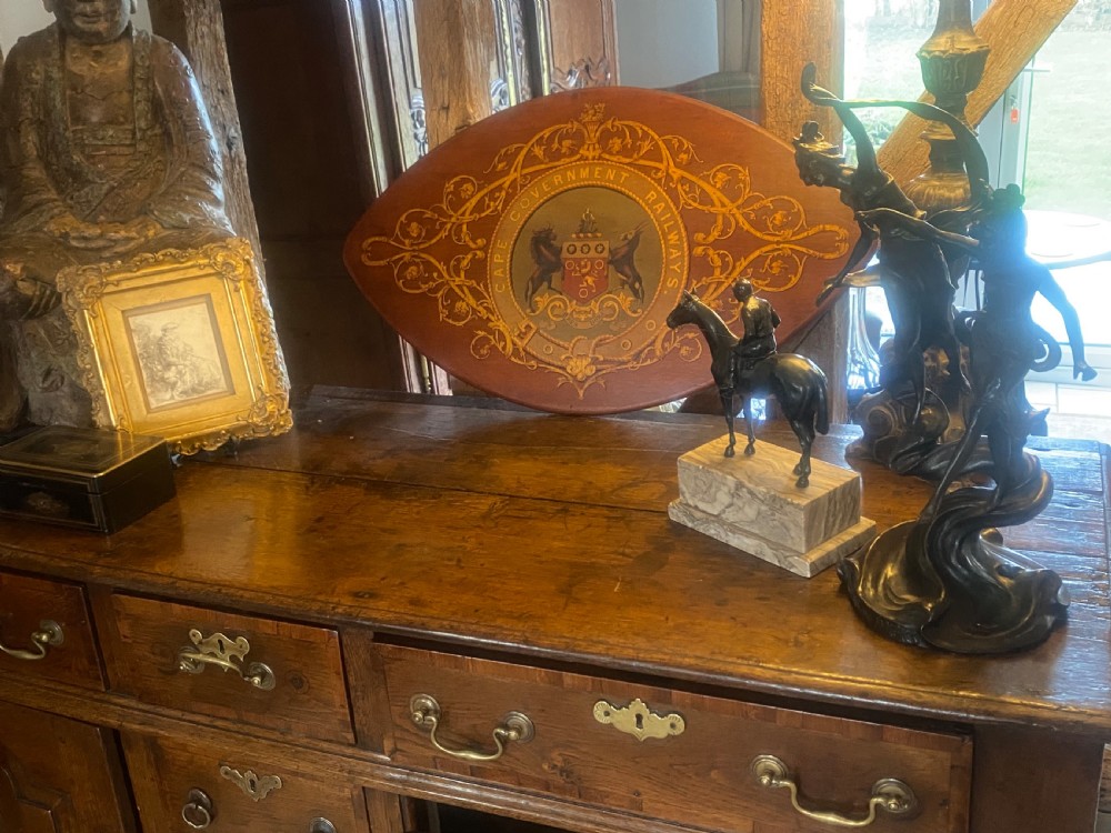 An oval dark wood plaque inscribed with Cape Government Railways featuring a painted coat of arms and gilded floral scrollwork. View VII