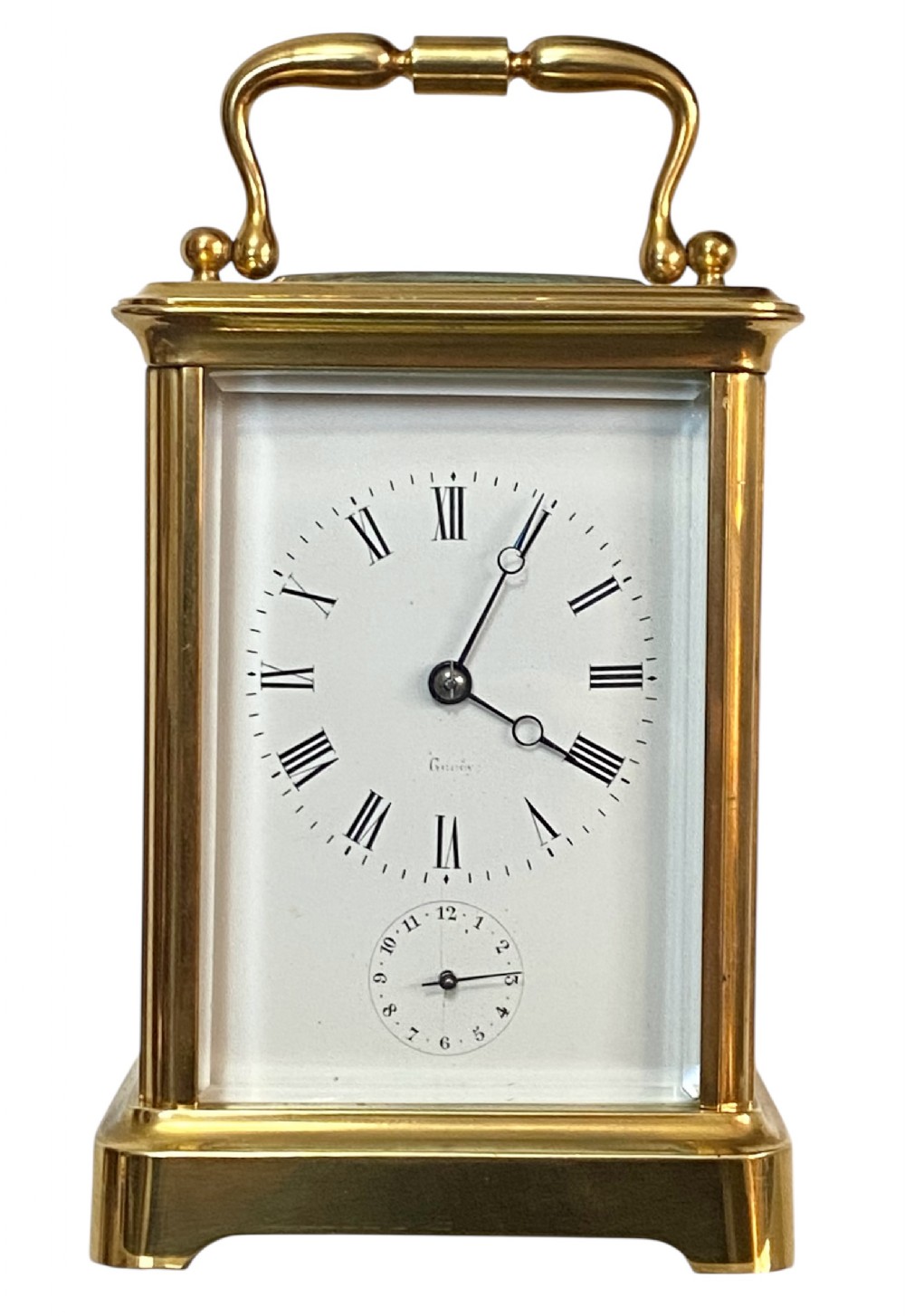 A rectangular gilt brass carriage clock featuring a folding top handle, white enamel dial with Roman numerals, and a lower auxiliary alarm dial.