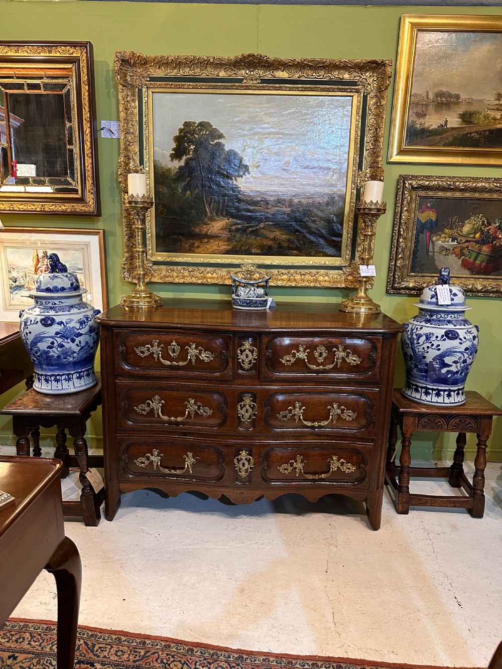 An 18th-century French oak serpentine chest of drawers featuring three rows of moulded drawer fronts and decorative brass handles. View III