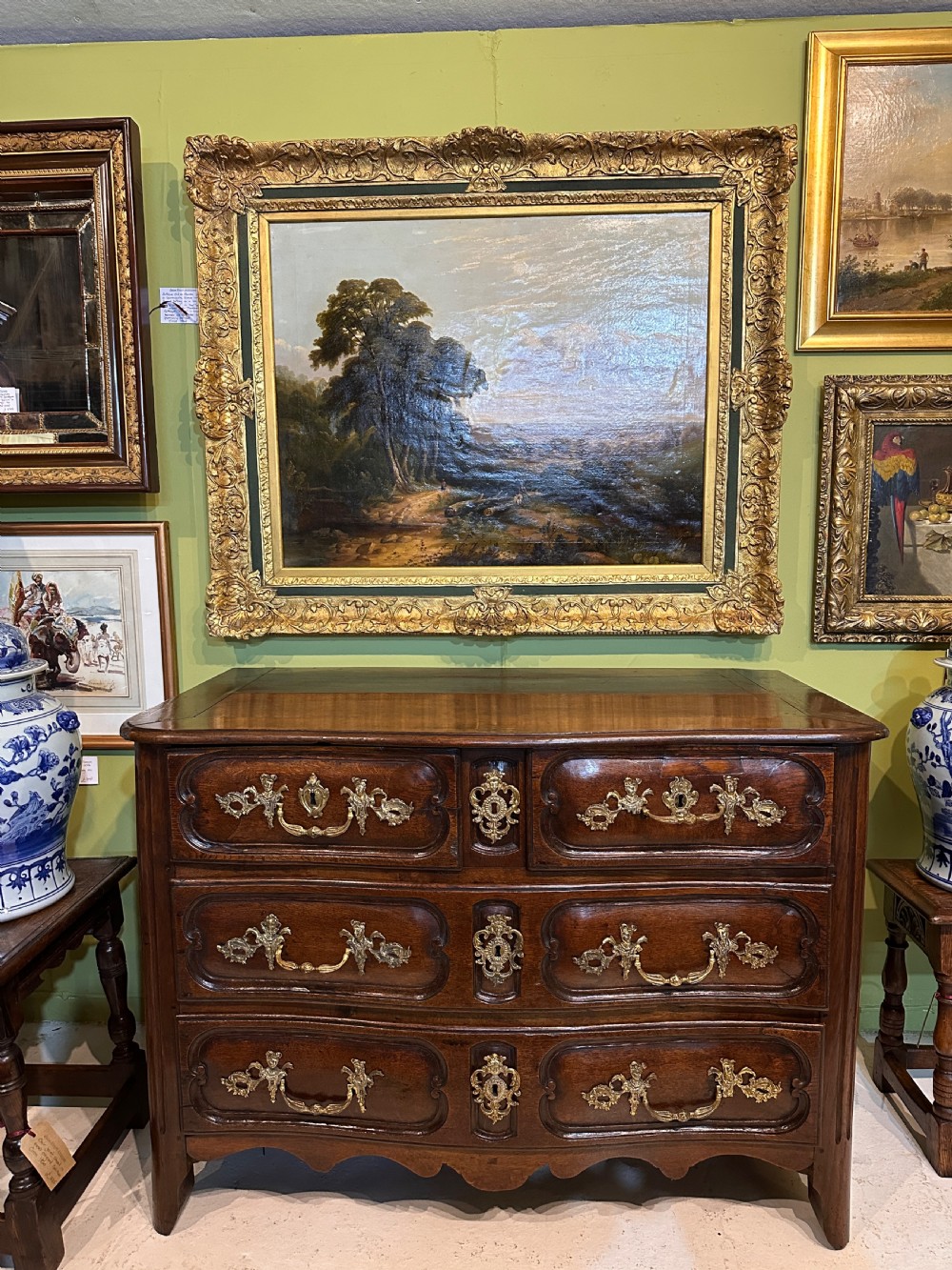 An 18th-century French oak serpentine chest of drawers featuring three rows of moulded drawer fronts and decorative brass handles. View XIII