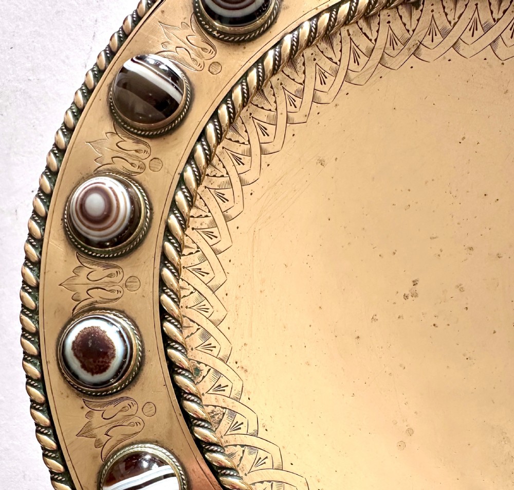 A shallow circular bronze pedestal tazza featuring an engraved interior rim and a border inset with polished banded agate cabochons. View II