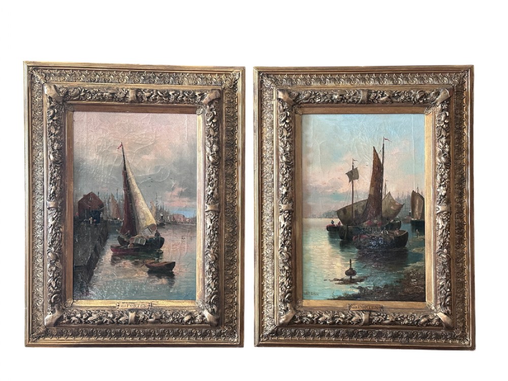A pair of framed oil paintings on canvas depicting wooden sailing boats docked in a harbour within ornate gold leaf frames.