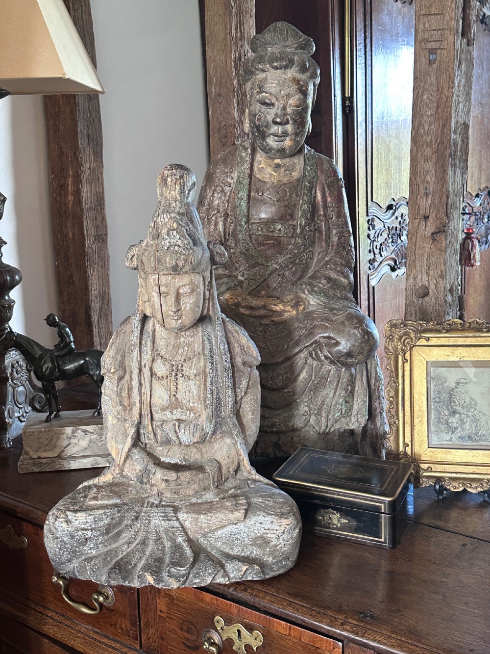 A carved wooden statue of a seated Buddha with a high headpiece and weathered finish. View X