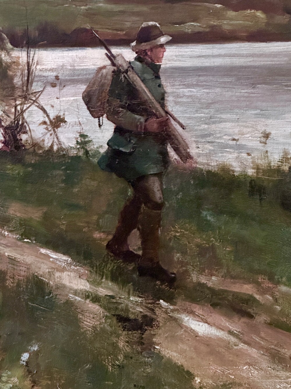 An antique late Victorian oil painting depicting a figure walking along a riverbank path in a rural countryside landscape, framed in a moulded giltwood frame. View IV