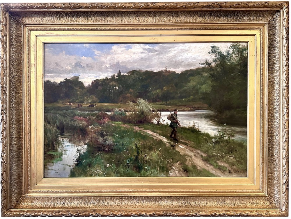 An antique late Victorian oil painting depicting a figure walking along a riverbank path in a rural countryside landscape, framed in a moulded giltwood frame.