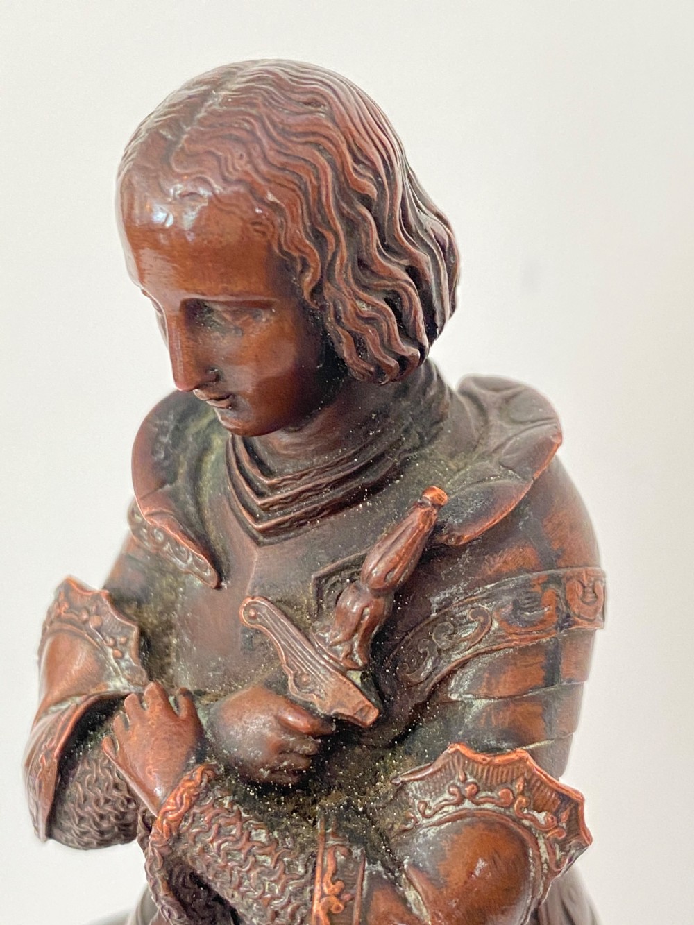 A 19th-century dark bronze sculpture depicting Joan of Arc in suit of armour with a sword, mounted on a round reddish marble base. View II