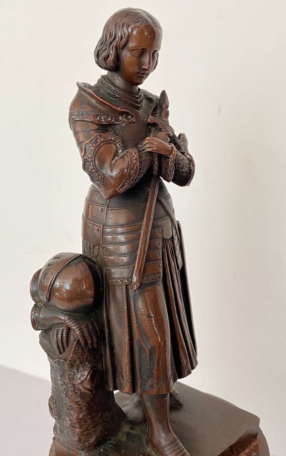 A 19th-century dark bronze sculpture depicting Joan of Arc in suit of armour with a sword, mounted on a round reddish marble base. View IV