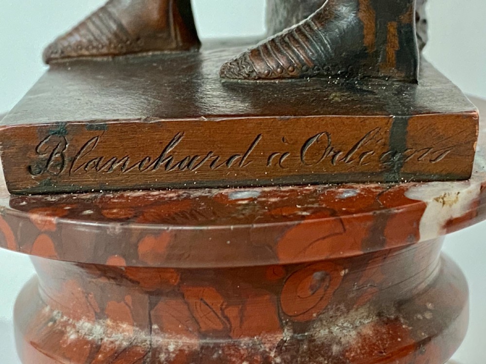 A 19th-century dark bronze sculpture depicting Joan of Arc in suit of armour with a sword, mounted on a round reddish marble base. View XII