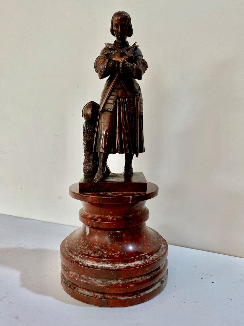 A 19th-century dark bronze sculpture depicting Joan of Arc in suit of armour with a sword, mounted on a round reddish marble base. View XIII