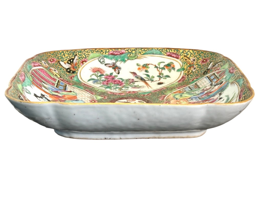 A square Chinese porcelain dish with lobed corners featuring painted reserves of figural court scenes, birds, and flowers set against a dense green scroll and butterfly ground. View III