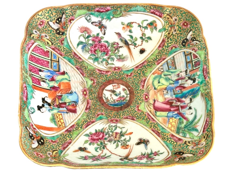 A square Chinese porcelain dish with lobed corners featuring painted reserves of figural court scenes, birds, and flowers set against a dense green scroll and butterfly ground. View IV