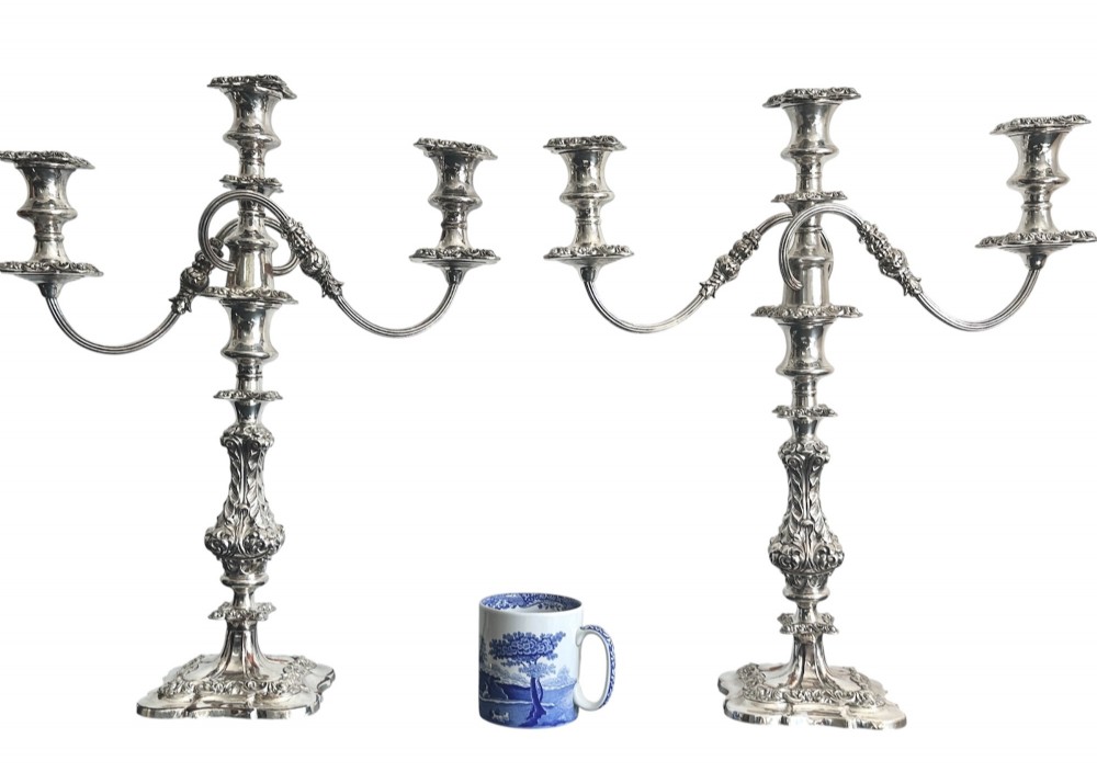 A matching pair of silver-plated three-light candelabra featuring ornate scroll-formed arms, foliate-moulded bases, and white taper candles. View III