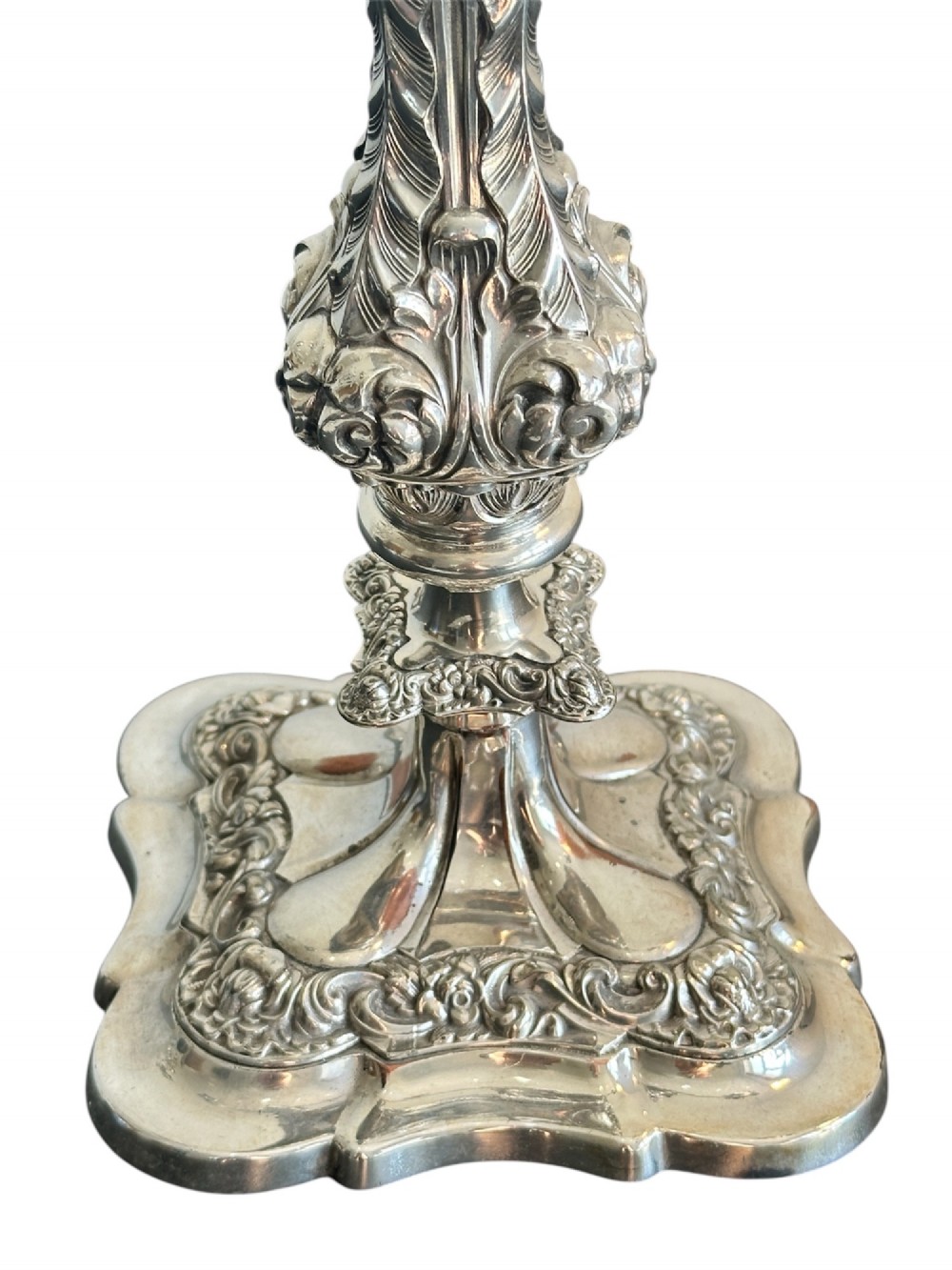 A matching pair of silver-plated three-light candelabra featuring ornate scroll-formed arms, foliate-moulded bases, and white taper candles. View V