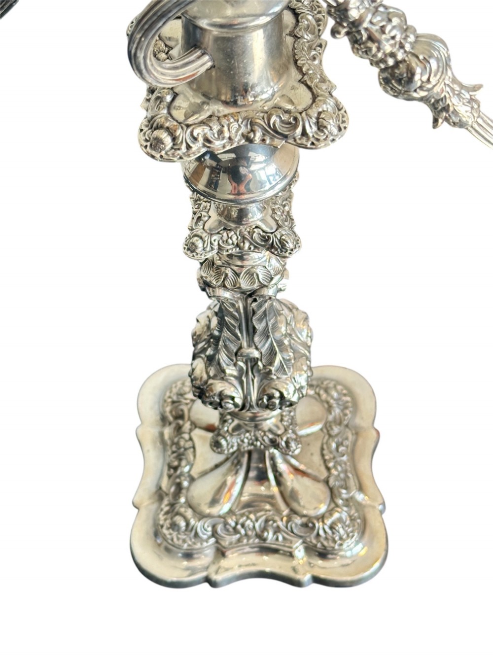 A matching pair of silver-plated three-light candelabra featuring ornate scroll-formed arms, foliate-moulded bases, and white taper candles. View VII