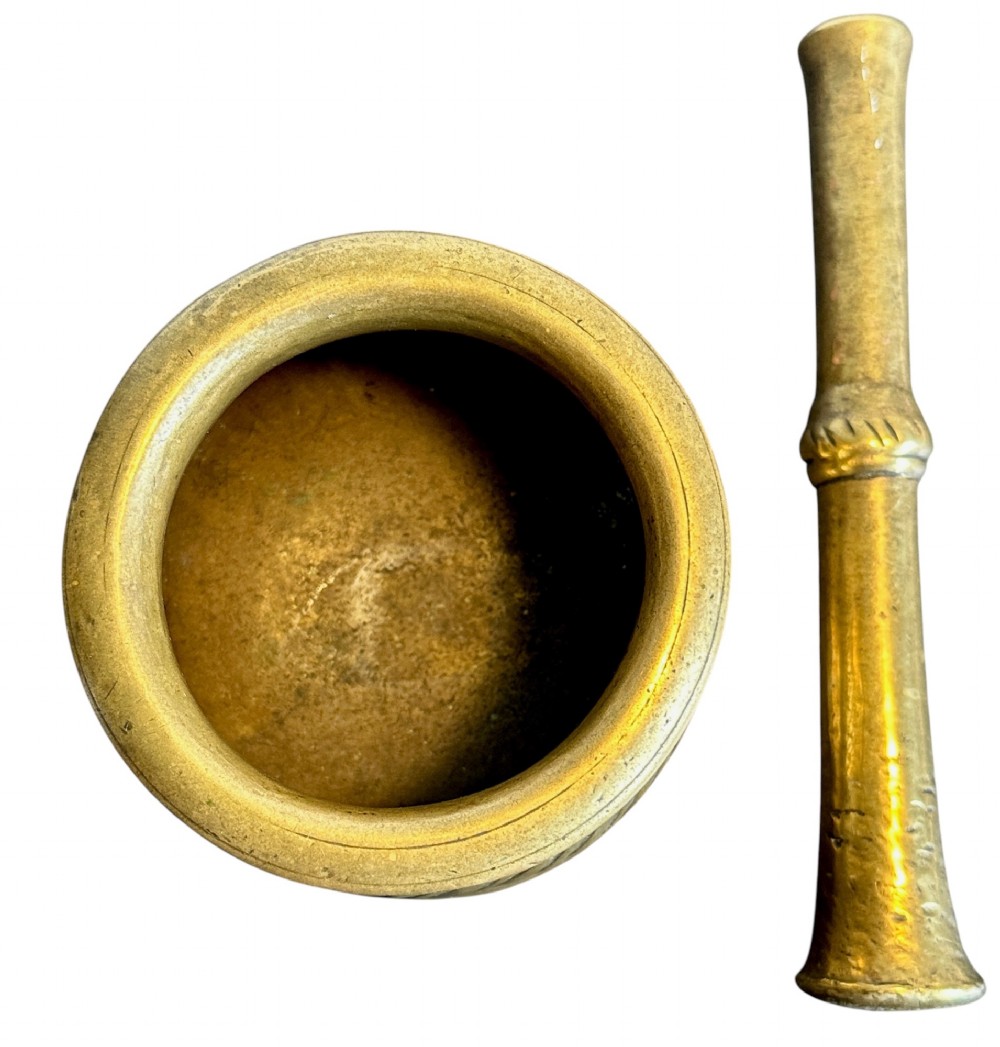 An eighteenth-century cast brass pestle and mortar featuring diagonal carved fluting around the main bowl and a flared rim. View II