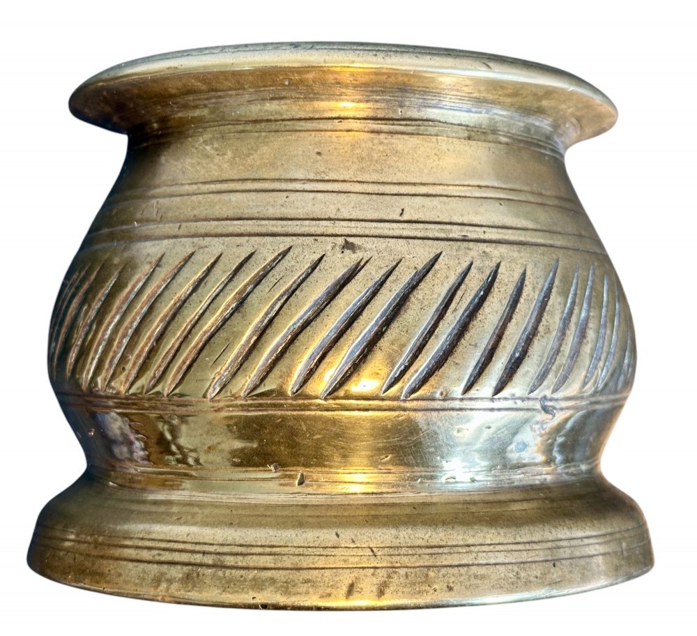 An eighteenth-century cast brass pestle and mortar featuring diagonal carved fluting around the main bowl and a flared rim. View III