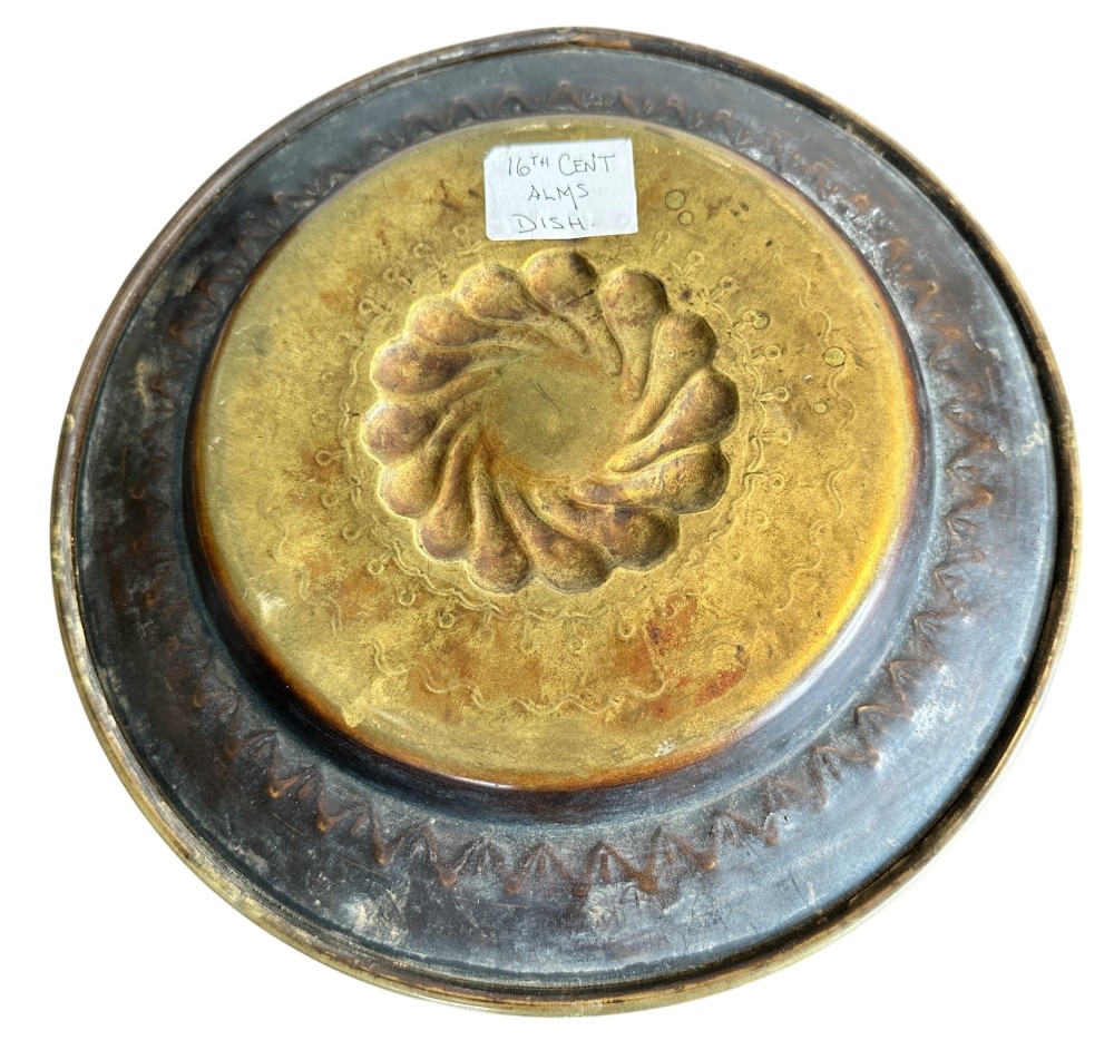 A circular brass alms dish featuring a central gadrooned swirl motif surrounded by punched geometric border patterns. View IV