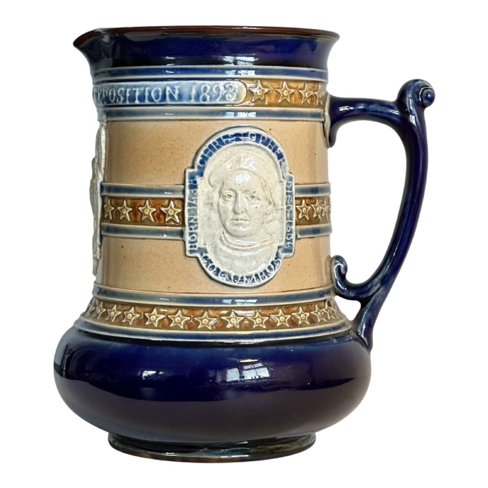 Doulton Lambeth salt-glazed stoneware jug featuring deep cobalt blue borders, buff central body, star motifs, and a relief portrait medallion of Christopher Columbus.