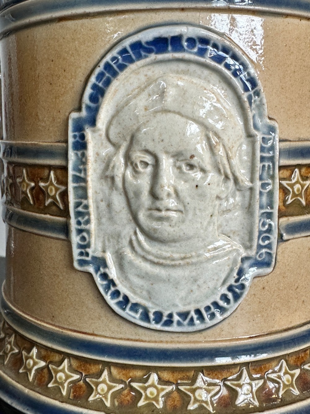 Doulton Lambeth salt-glazed stoneware jug featuring deep cobalt blue borders, buff central body, star motifs, and a relief portrait medallion of Christopher Columbus. View IV
