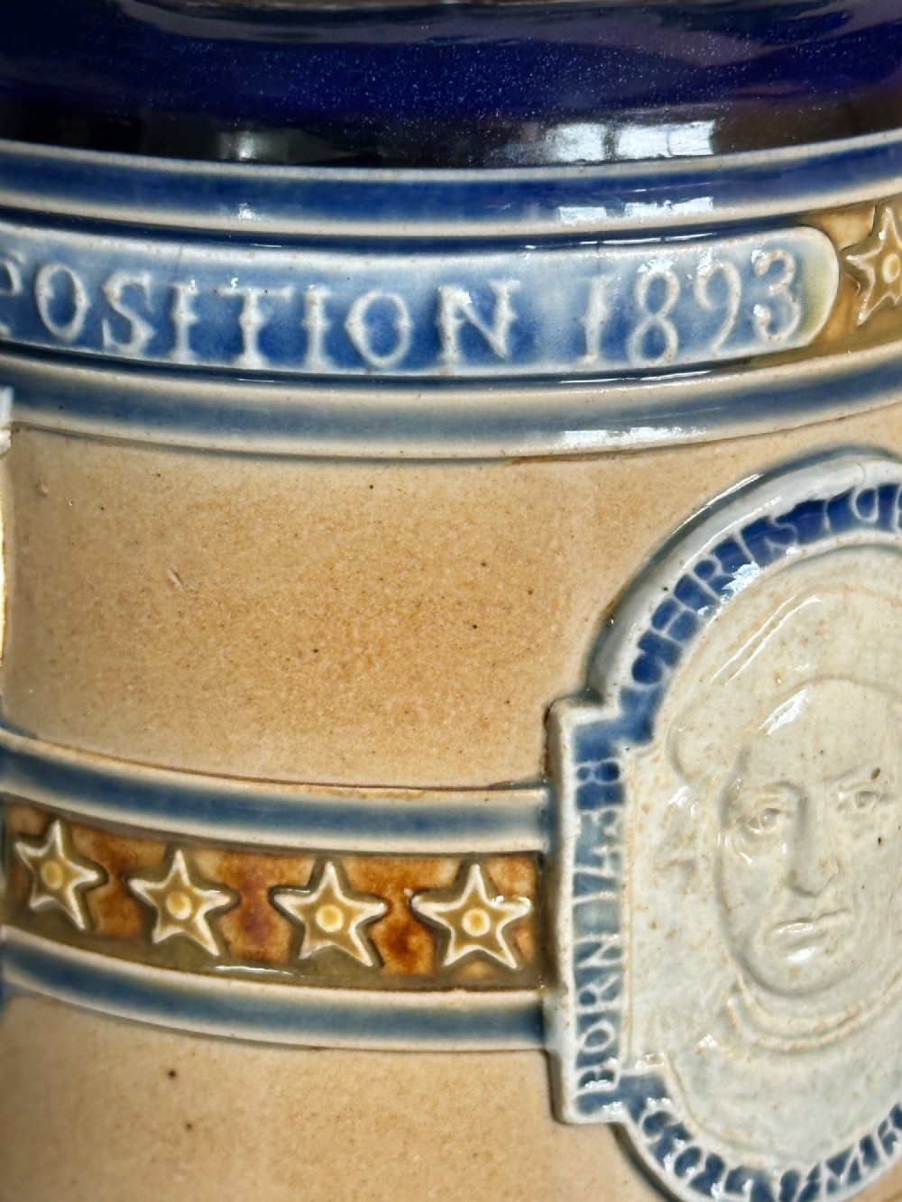 Doulton Lambeth salt-glazed stoneware jug featuring deep cobalt blue borders, buff central body, star motifs, and a relief portrait medallion of Christopher Columbus. View VI