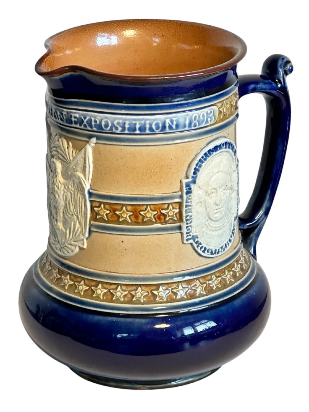 Doulton Lambeth salt-glazed stoneware jug featuring deep cobalt blue borders, buff central body, star motifs, and a relief portrait medallion of Christopher Columbus. View IX
