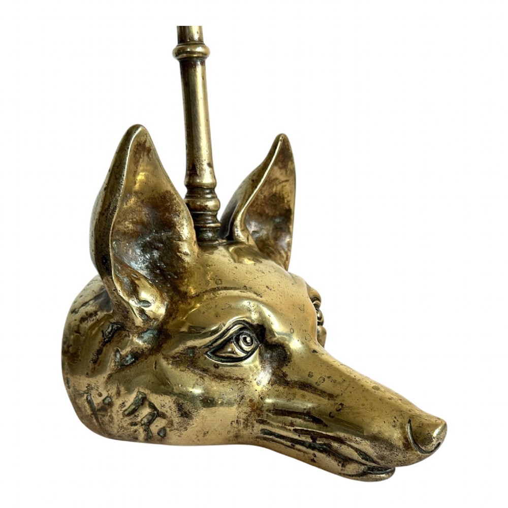 A cast brass doorstop shaped as a fox head with an attached vertical shaft ending in an oval handle. View II