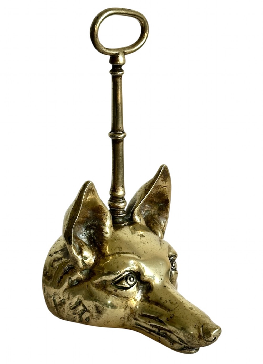 A cast brass doorstop shaped as a fox head with an attached vertical shaft ending in an oval handle.