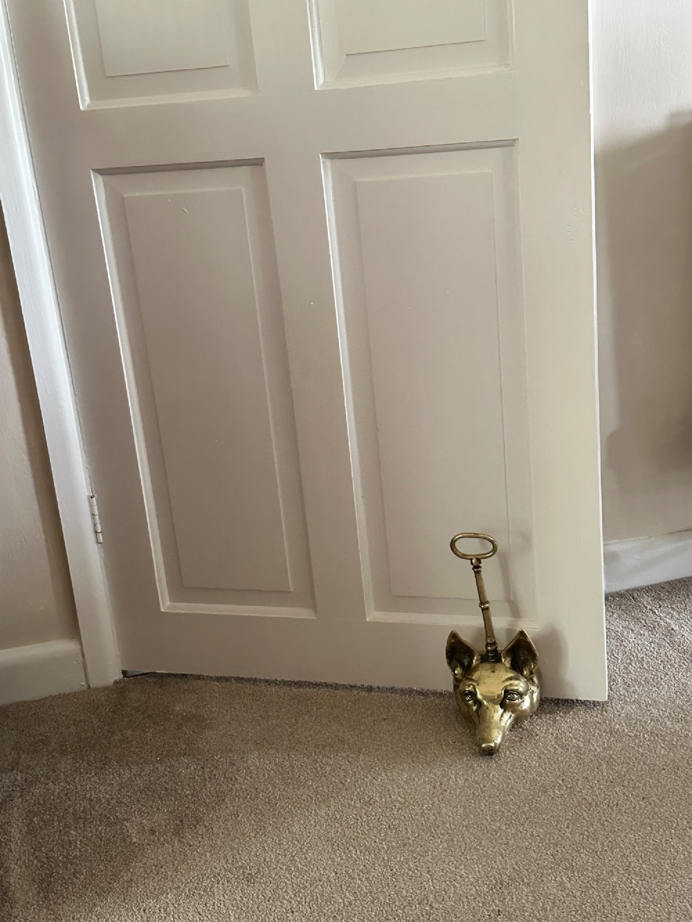 A cast brass doorstop shaped as a fox head with an attached vertical shaft ending in an oval handle. View VII