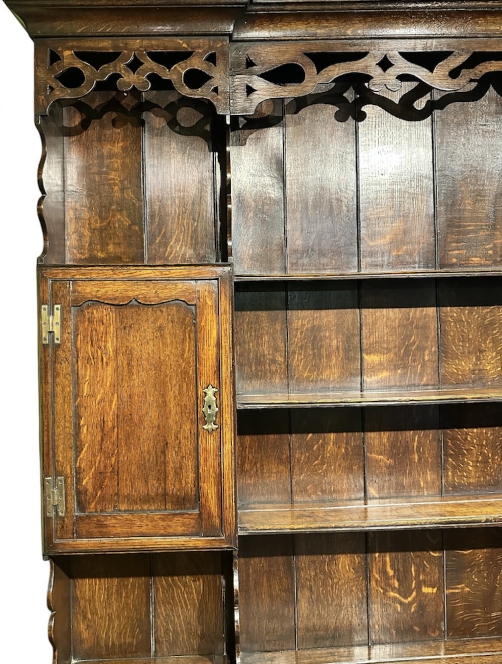 A dark oak George III dresser featuring an open plate rack top with side cupboards above three base drawers supported on cabriole legs. View IV