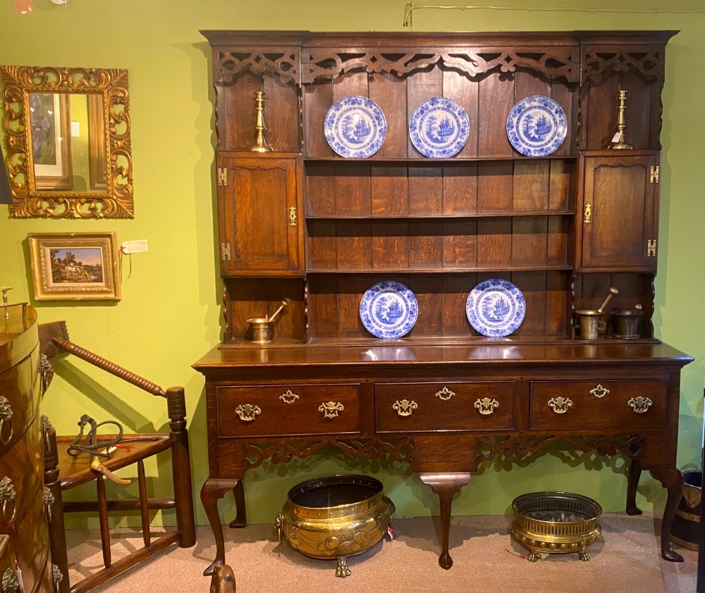 A dark oak George III dresser featuring an open plate rack top with side cupboards above three base drawers supported on cabriole legs. View XII