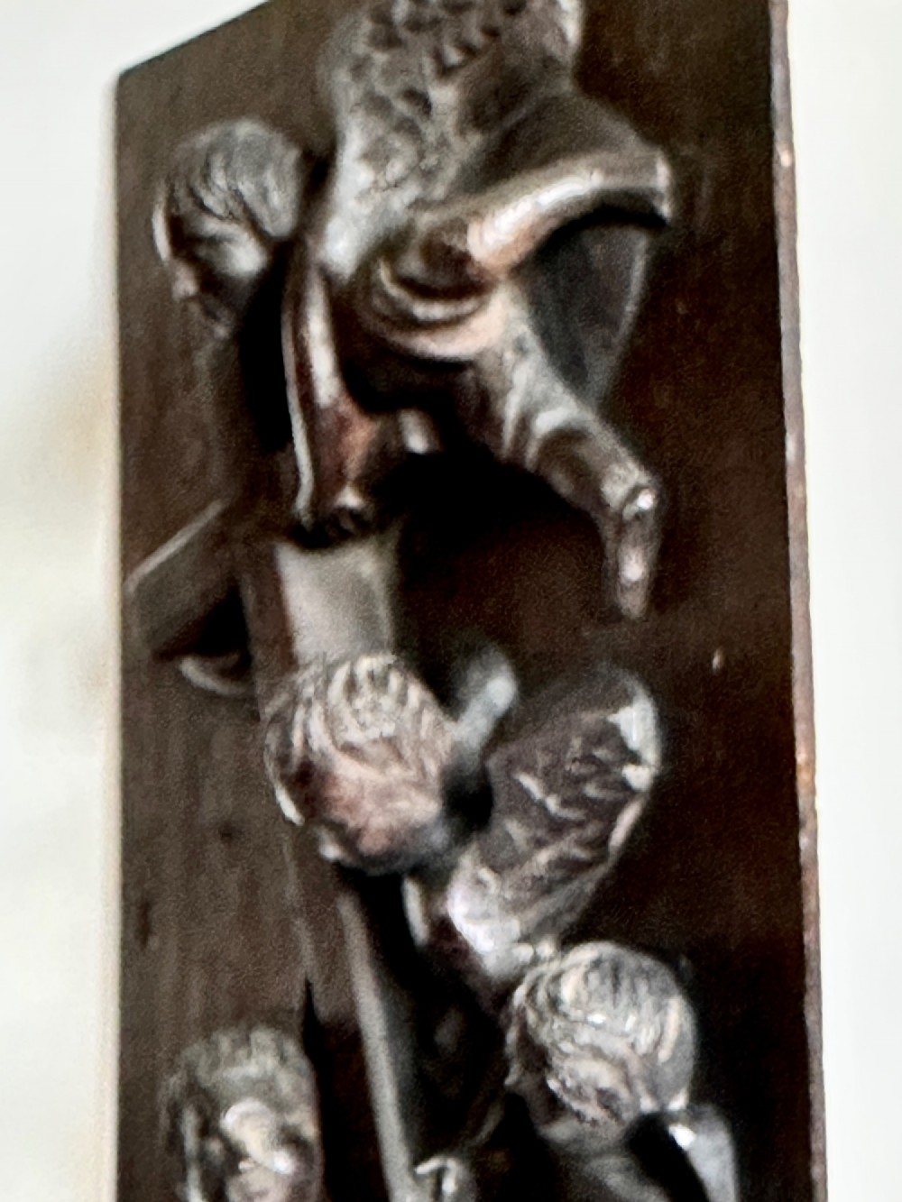 A rectangular dark oak timber panel featuring a high-relief carving of cherubs surrounding a large wooden cross. View VIII