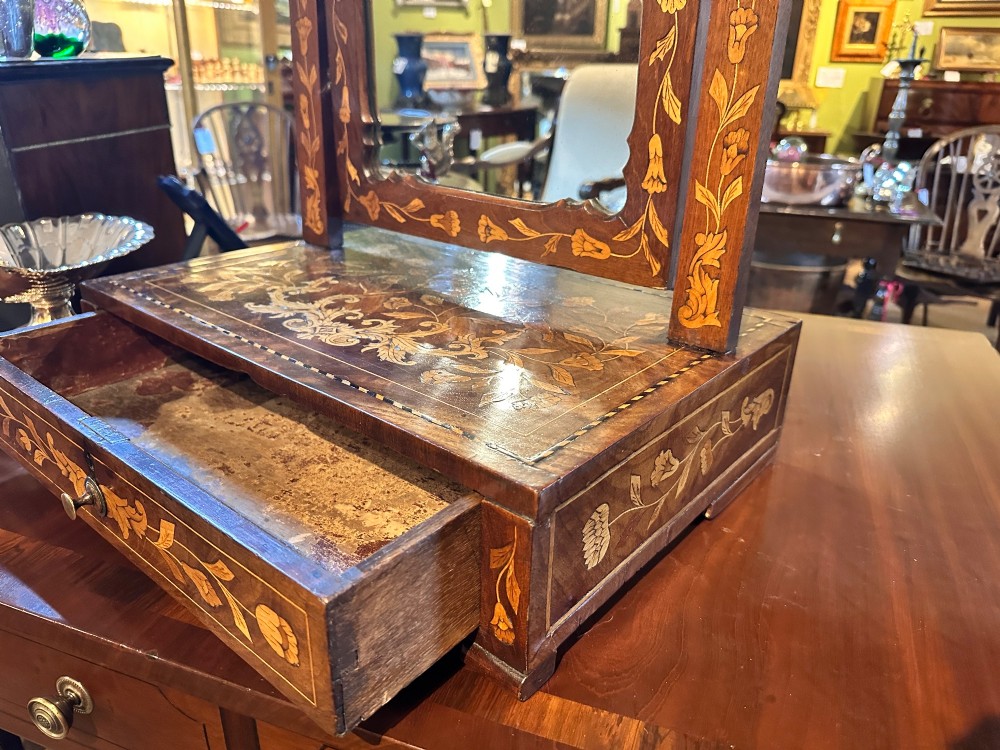 An antique Dutch walnut dressing table mirror featuring intricate floral marquetry inlay across the frame, support posts, and single-drawer base. View V