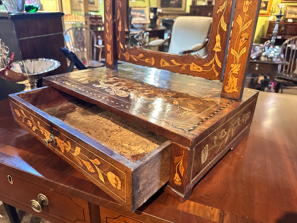 An antique Dutch walnut dressing table mirror featuring intricate floral marquetry inlay across the frame, support posts, and single-drawer base. View VI