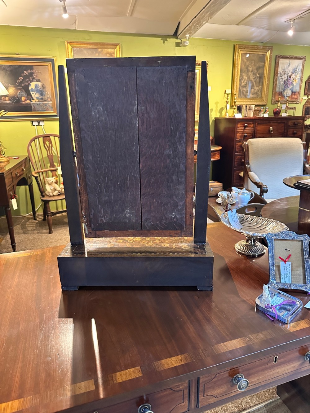 An antique Dutch walnut dressing table mirror featuring intricate floral marquetry inlay across the frame, support posts, and single-drawer base. View VII