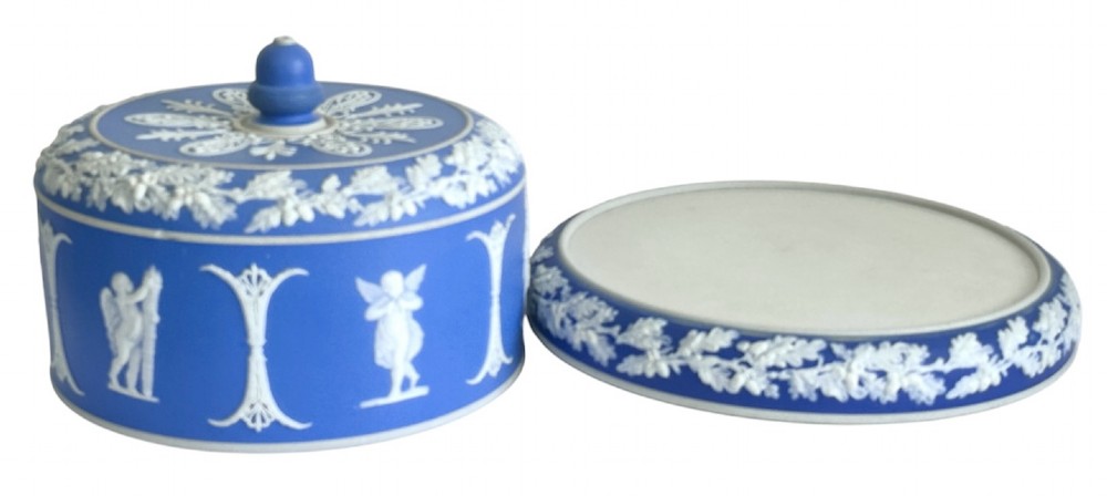 A Victorian blue Jasperware cheese dome and base decorated with white neoclassical figures, oak leaf garlands, and a central finial handle. View V
