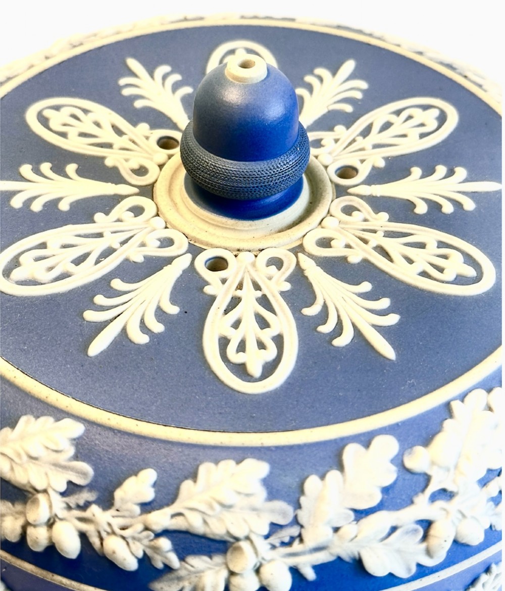 A Victorian blue Jasperware cheese dome and base decorated with white neoclassical figures, oak leaf garlands, and a central finial handle. View X