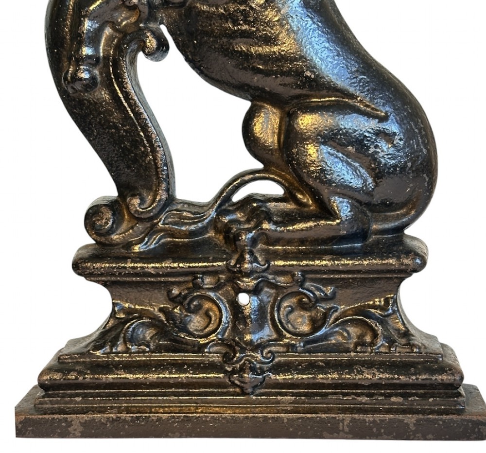A side profile view of a dark cast iron doorstop depicting a rampant lion mounted on a stepped rectangular base. View V