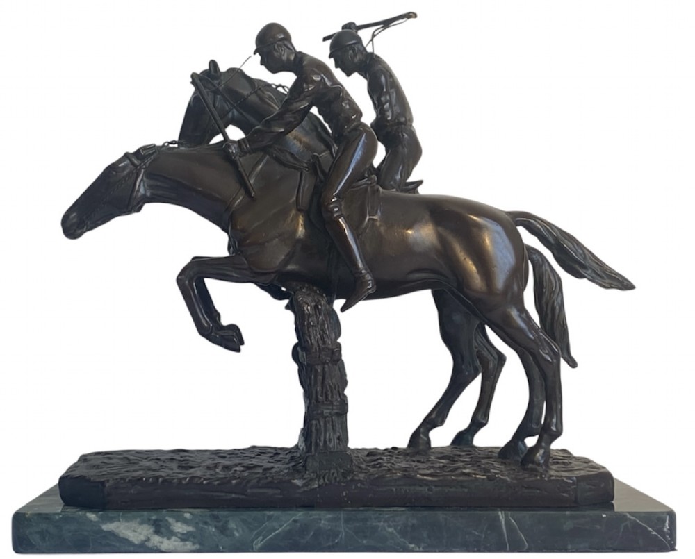 A dark brown bronze sculpture depicting two racehorses and jockeys clearing a fence during a steeplechase, mounted on a polished green marble base.