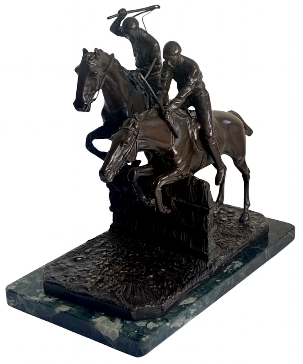 A dark brown bronze sculpture depicting two racehorses and jockeys clearing a fence during a steeplechase, mounted on a polished green marble base. View IV