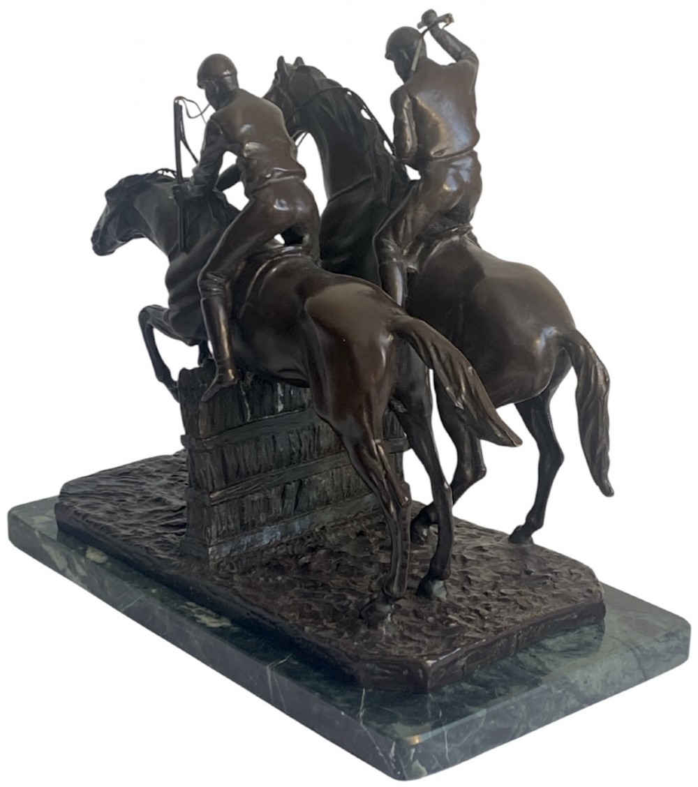 A dark brown bronze sculpture depicting two racehorses and jockeys clearing a fence during a steeplechase, mounted on a polished green marble base. View V