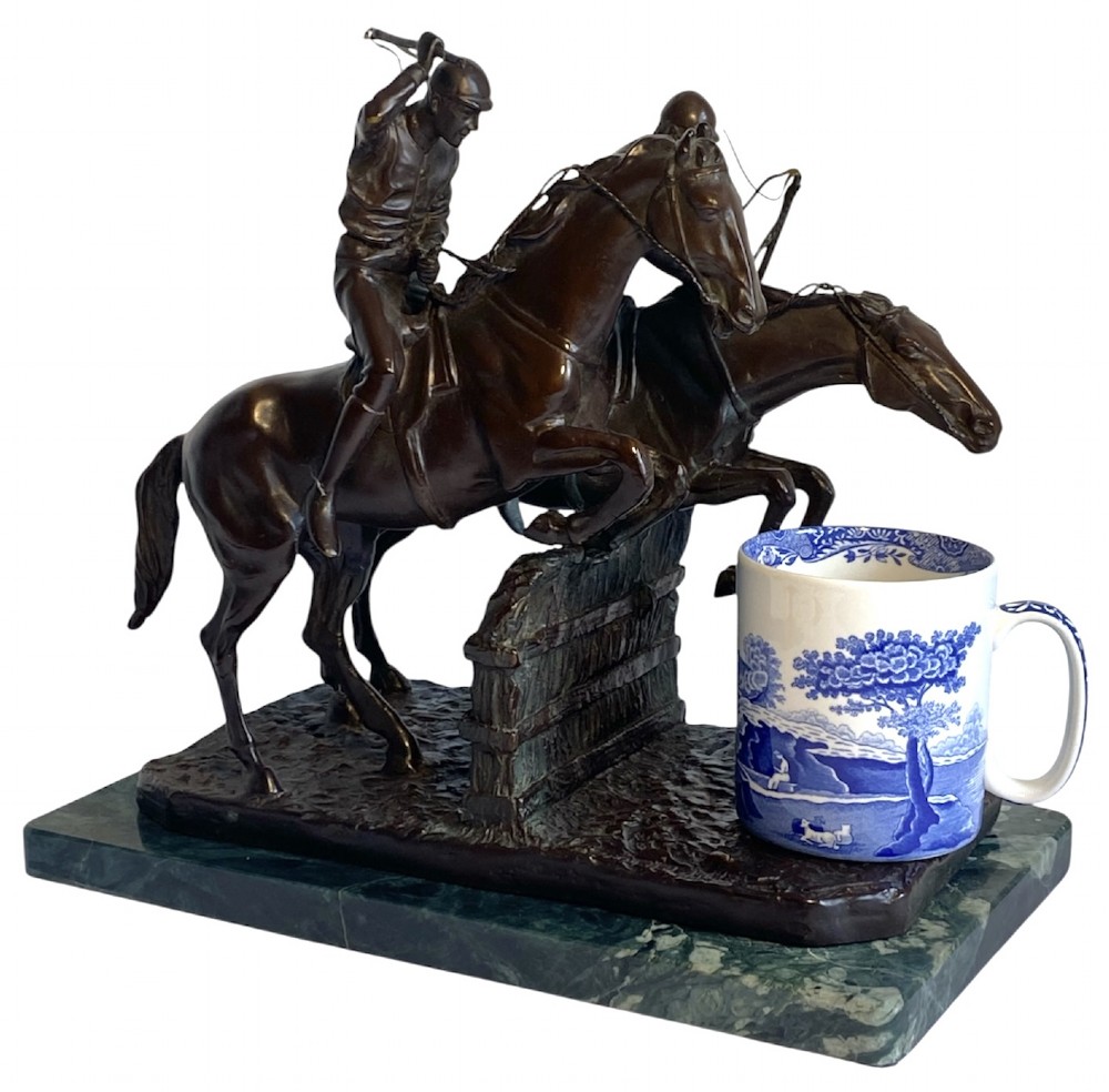 A dark brown bronze sculpture depicting two racehorses and jockeys clearing a fence during a steeplechase, mounted on a polished green marble base. View VII