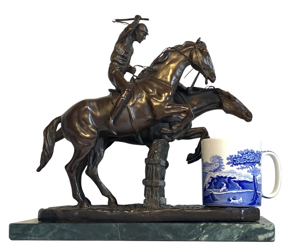 A dark brown bronze sculpture depicting two racehorses and jockeys clearing a fence during a steeplechase, mounted on a polished green marble base. View XI