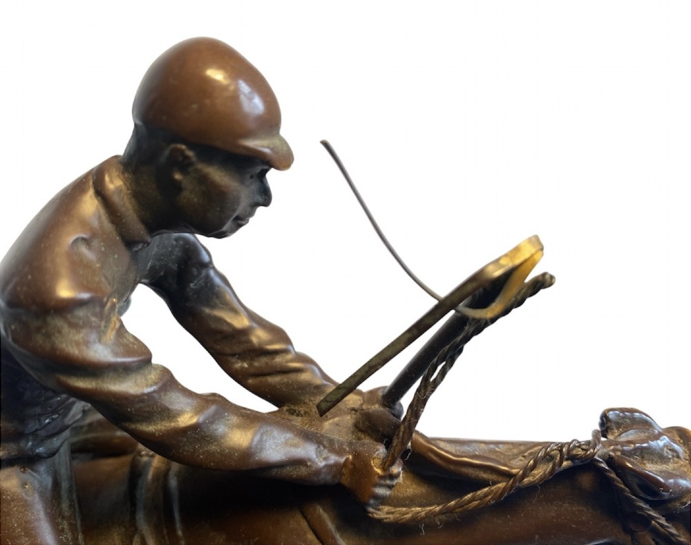 A dark brown bronze sculpture depicting two racehorses and jockeys clearing a fence during a steeplechase, mounted on a polished green marble base. View XII