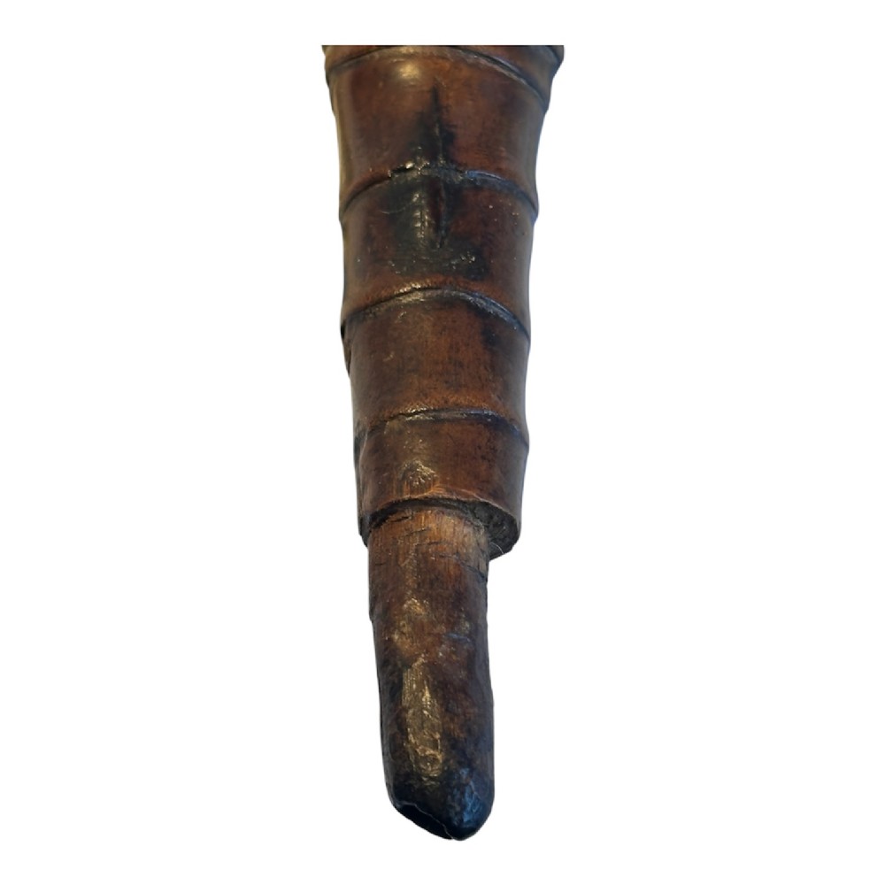 A dark brown carved bamboo smoking pipe shaped into a figurative human form along the bowl with a tapered bamboo stem. View VI